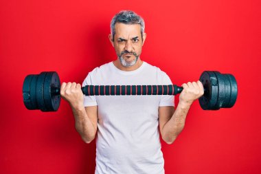 Yakışıklı, orta yaşlı, gri saçlı spor giyimli, halterci, kuşkucu ve gergin, sorun yüzünden üzgün. negatif kişi. 