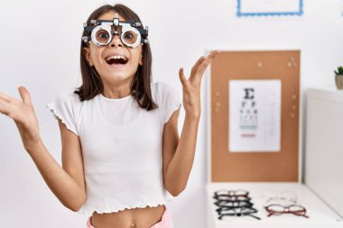 Optometri gözlüğü takan genç İspanyol kız zaferi mutlu bir gülümsemeyle ve kazanan yüz ifadesiyle kutluyor. 