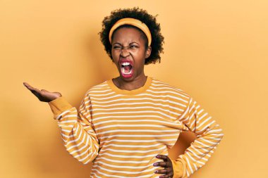 Genç Afro-Amerikalı kadın avuçlarını açmış kızgın ve kızgın bir şey tutuyor sinirli ve öfkeli bir şekilde bağırıyor, öfkeyle bağırıyor. öfke ve agresif konsept. 