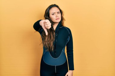 Genç İspanyol kız dalgıç neoprene üniforması giyiyor mutsuz görünüyor ve reddedilmiş ve olumsuz bir hareket sergiliyor. kötü ifade. 