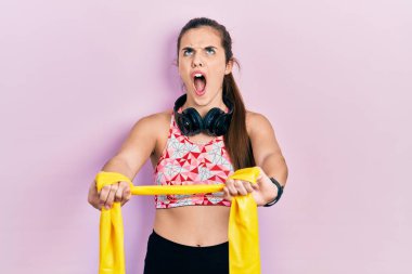 Genç esmer kız, kol bantlarıyla kol direnci geliştiriyor. Kızgın ve kızgın çığlıklar atıyor. Öfkeyle bağırıyor, öfkeyle yukarı bakıyor.. 