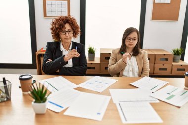 Ofiste çalışan iki kadın grubu. Olgun kadın ve Down sendromlu kız kapsayıcı takım çalışması yapıyor..