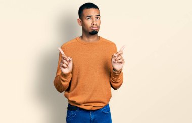 Genç Afro-Amerikan adam günlük giysiler giymiş üzgün ve üzgün görünüyor, parmaklarıyla yön gösteriyor, mutsuz ve depresif.. 