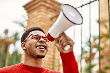 Yakışıklı Afrikalı Amerikalı genç adam megafonla bağırıyor.