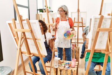 Resim stüdyosunda resim çizen bir grup orta yaşlı öğrenci. Öğretmen görünümlü öğrenci çizimi.