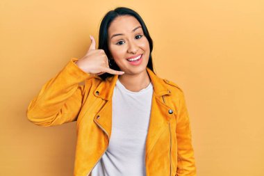 Burnuna piercing takan, sarı deri ceket giyen, el ve parmaklarıyla telefonla konuşan güzel İspanyol bir kadın. iletişim kavramları. 