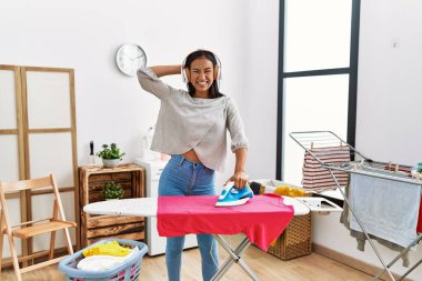 Çamaşır odasında müzik dinleyen genç Latin kadın.