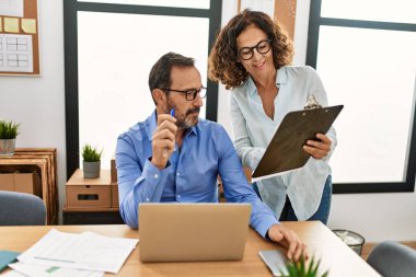 Ofiste çalışırken gülümseyen iki orta yaşlı iş adamı..