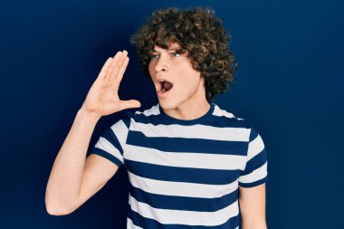 Sıradan çizgili tişört giyen yakışıklı genç adam el ve ağızla bağırıyor ve bağırıyordu. iletişim konsepti. 