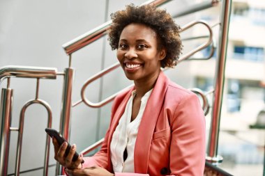 Güzel iş kadını afro saçlı Afro-Amerikan kadın mutlu ve kendinden emin bir şekilde gülümsüyor.