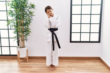 Karate kimonosu ve siyah kuşak giyen genç İspanyol kız uyumaktan yorgun düşler kurup el ele poz verirken kapalı gözlerle gülümsüyor.. 