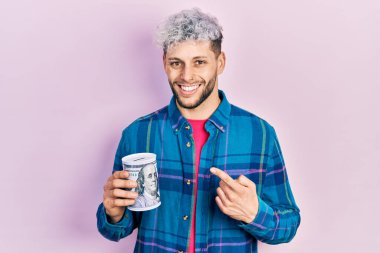 Modern boyalı saçlı, kumbaralı, gülümseyen, el ve parmağıyla işaret eden genç bir İspanyol. 