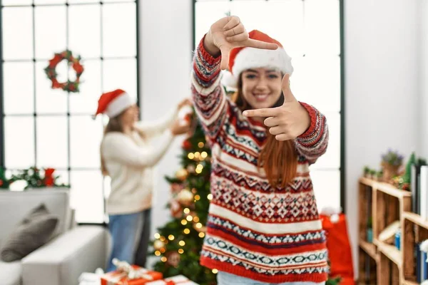 クリスマスツリーの笑顔で家に立つ美しいカップルは 幸せな顔で手と指でフレームを作ります 創造性と写真の概念 — ストック写真
