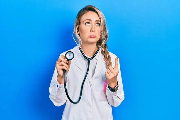 Krásná Mladá Blondýnka Doktorka Drží Stetoskop Ukazuje Nahoru Vypadá Smutně — Stock fotografie