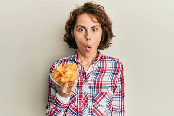 Junge Brünette Frau Mit Kartoffelchips Der Hand Verängstigt Und Erstaunt — Stockfoto