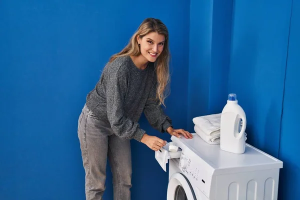 Νεαρή Ξανθιά Γυναίκα Χαμογελαστή Αυτοπεποίθηση Ρίχνει Απορρυπαντικό Στο Πλυντήριο — Φωτογραφία Αρχείου
