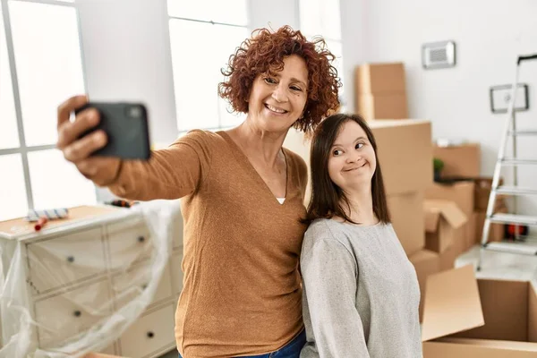 熟女の母とダウン症候群の娘は新しい家に移動し 段ボール箱のそばに立って写真を撮る — ストック写真