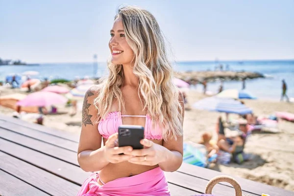 Mladá Blondýna Dívka Pomocí Smartphone Sedí Lavičce Pláži — Stock fotografie