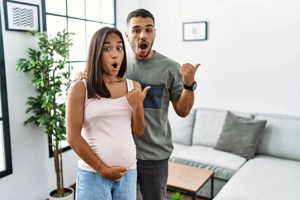 Joven Pareja Interracial Esperando Bebé Tocando Vientre Embarazada Sorprendida Apuntando — Foto de Stock