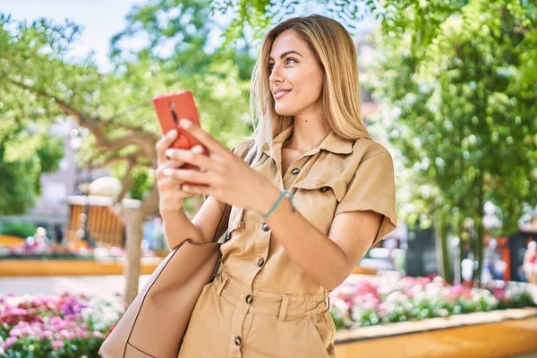 若いですブロンド女の子笑顔幸せな使用スマートフォンで街 — ストック写真