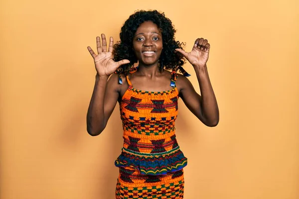 自信を持って幸せな笑顔ながら 伝統的なアフリカの服を着て 指の数6で指摘している若いアフリカ系アメリカ人女性 — ストック写真