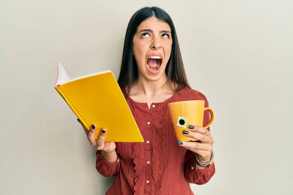 Mujer Hispana Joven Leyendo Libro Bebiendo Taza Enojado Loco Gritando — Foto de Stock