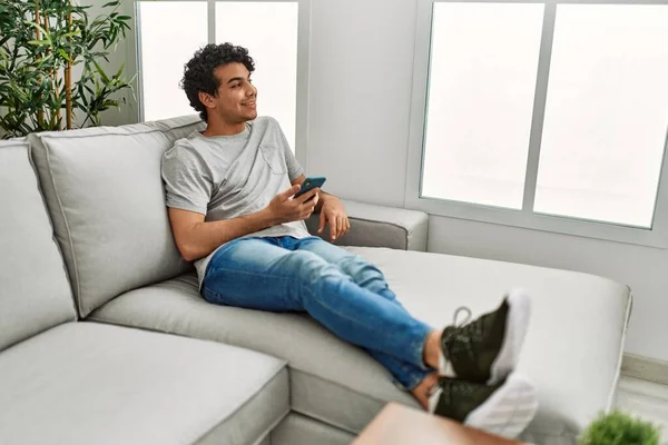 Ung Latinamerikan Man Med Smartphone Sitter Soffan Hemma — Stockfoto