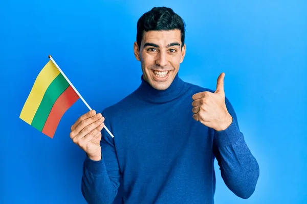 リトアニアの旗を持っているハンサムなヒスパニック系の男笑顔と正 親指アップ行う優れた承認サイン — ストック写真