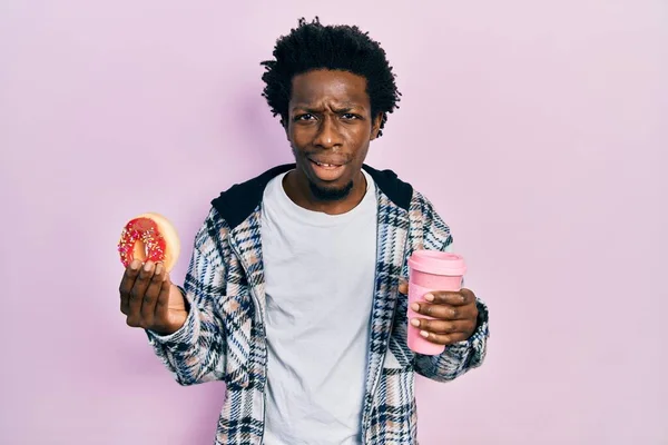 Junger Afrikanisch Amerikanischer Mann Isst Donut Und Trinkt Kaffee Ahnungslos — Stockfoto