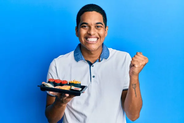 Joven Hombre Hispano Guapo Mostrando Plato Sushi Gritando Orgulloso Celebrando — Foto de Stock