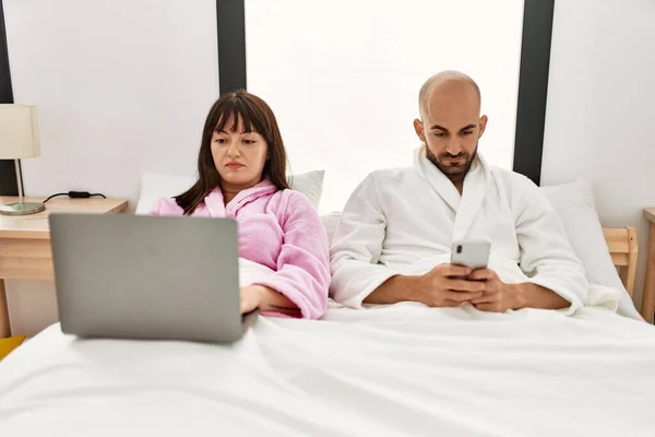 Genç Spanyol Çift Yatak Odasındaki Yatakta Dizüstü Bilgisayar Akıllı Telefon — Stok fotoğraf