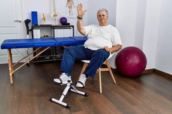 Homem Caucasiano Sênior Clínica Fisioterapia Usando Exercitador Pedal Mostrando Apontando — Fotografia de Stock