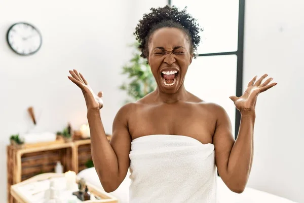 若いアフリカ系アメリカ人女性の美容センターで腕を上げ 興奮して叫んで目を閉じて成功のために狂気と狂気を祝うタオルを着て 勝者のコンセプト — ストック写真