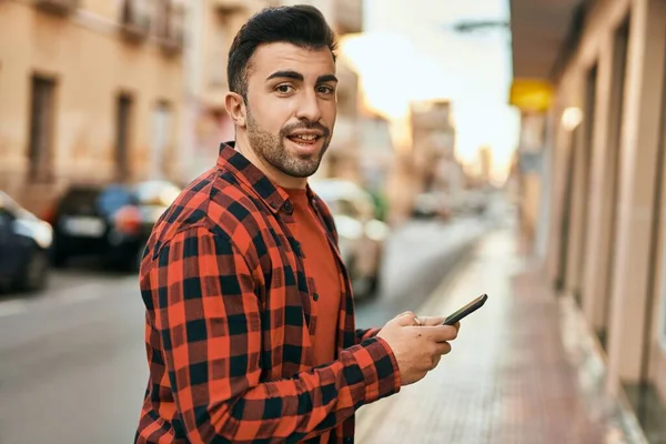 Joven Hombre Hispano Sonriendo Feliz Usando Smartphone Ciudad —  Fotos de Stock