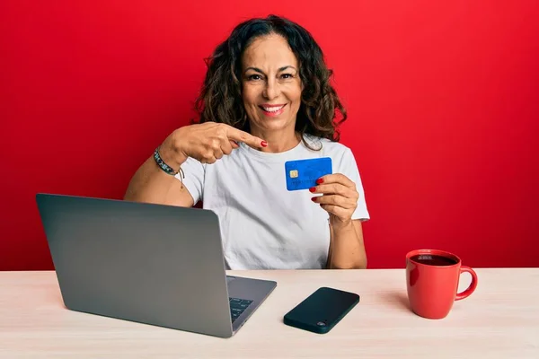 漂亮的中年女性在办公室工作时 用笔记本电脑和信用卡开心地微笑着 用手和手指指指点点 — 图库照片