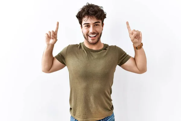 Hispánec Stojí Nad Osamělým Bílým Pozadím Usmívá Překvapen Ukazuje Prsty — Stock fotografie