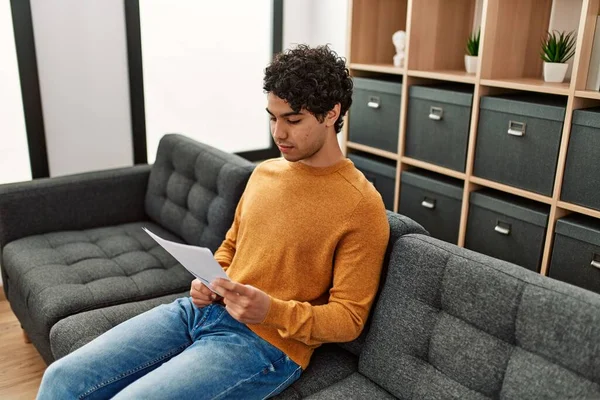 Young Hispanic Man Reading Paperwork Sitting Sofa Home — Stock Photo, Image