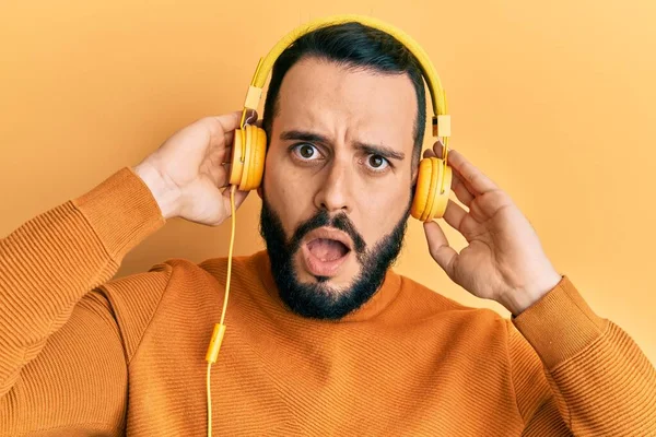 Νεαρός Άνδρας Γενειάδα Ακούγοντας Μουσική Χρησιμοποιώντας Ακουστικά Στο Πρόσωπο Σοκ — Φωτογραφία Αρχείου
