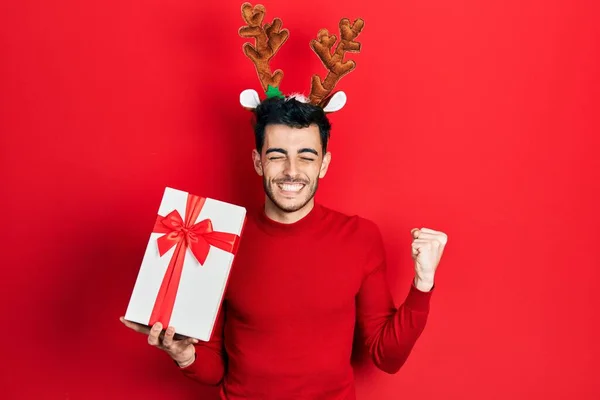 Fiatal Spanyol Férfi Visel Aranyos Karácsonyi Rénszarvas Szarv Kezében Ajándékokat — Stock Fotó