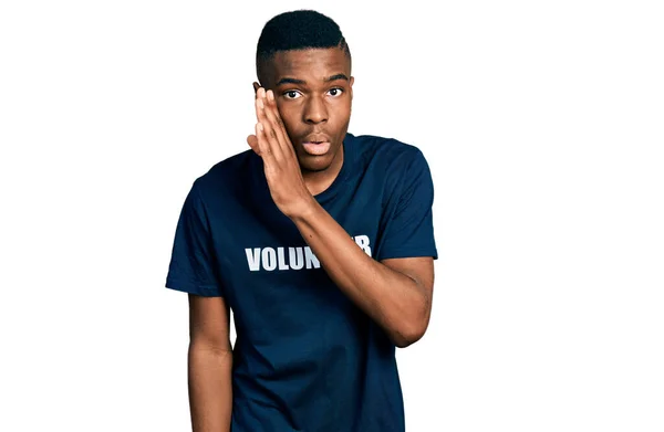 ボランティアのTシャツを着た若いアフリカ系アメリカ人男性が秘密噂を口にし悪意のある会話をささやく — ストック写真