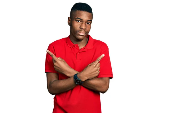指で両側を指すカジュアルな赤のTシャツを着ている若いアフリカ系アメリカ人男性 異なる方向は反対 — ストック写真