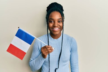 Saçları örgülü, elinde Fransa bayrağı olan Afro-Amerikan bir kadın. Olumlu ve mutlu görünüyor. Kendine güvenen bir gülümsemeyle dişlerini gösteriyor. 