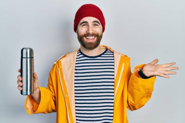 Sakallı, termosu olan beyaz adam başarıyı mutlu bir gülümsemeyle kutluyor ve kazanan el kaldırarak ifade ediyor. 