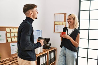 İki iş adamı gülümsüyor, ofiste kahve içiyorlar..