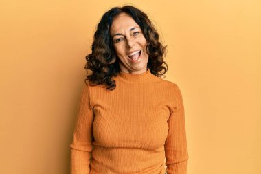 Orta yaşlı İspanyol kadın gündelik giysiler içinde kameraya seksi bir ifadeyle bakıyor, neşeli ve mutlu bir yüzle.. 