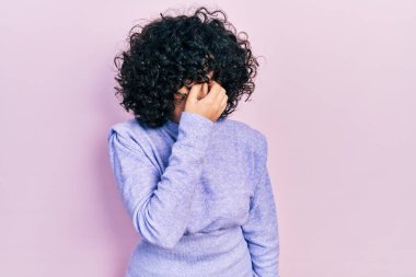 Orta Doğulu genç bir kadın günlük kıyafetler giyip yorgun burnu ve gözleri ovuşturup yorgun ve baş ağrısı çekiyor. Stres ve hüsran kavramı. 