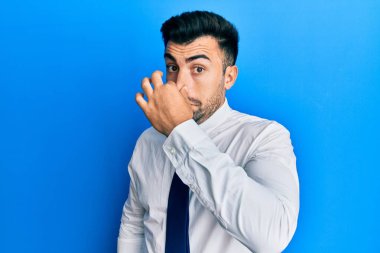 Genç İspanyol bir adam iş kıyafetleri giyip pis ve iğrenç bir koku alıyor. Nefesini burnunda tutuyor. Kötü kokuyor. 