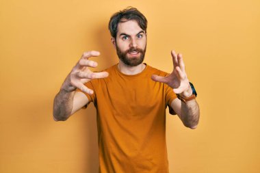 Sakallı, sarı tişörtlü beyaz bir adam öfkeyle bağırıyor, elleri boğmaya çalışıyor, deli gibi bağırıyor. 