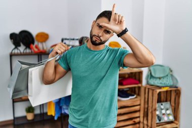 Satış mağazasında sakallı, alışveriş torbası tutan genç yakışıklı bir adam. Alnında parmakları olan insanlarla dalga geçiyor. Ezik hareketler yapıyor, alay ediyor.. 