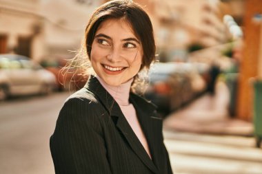 Genç ve güzel bir iş kadını gülümseyerek şehirde mutlu mesut duruyor..